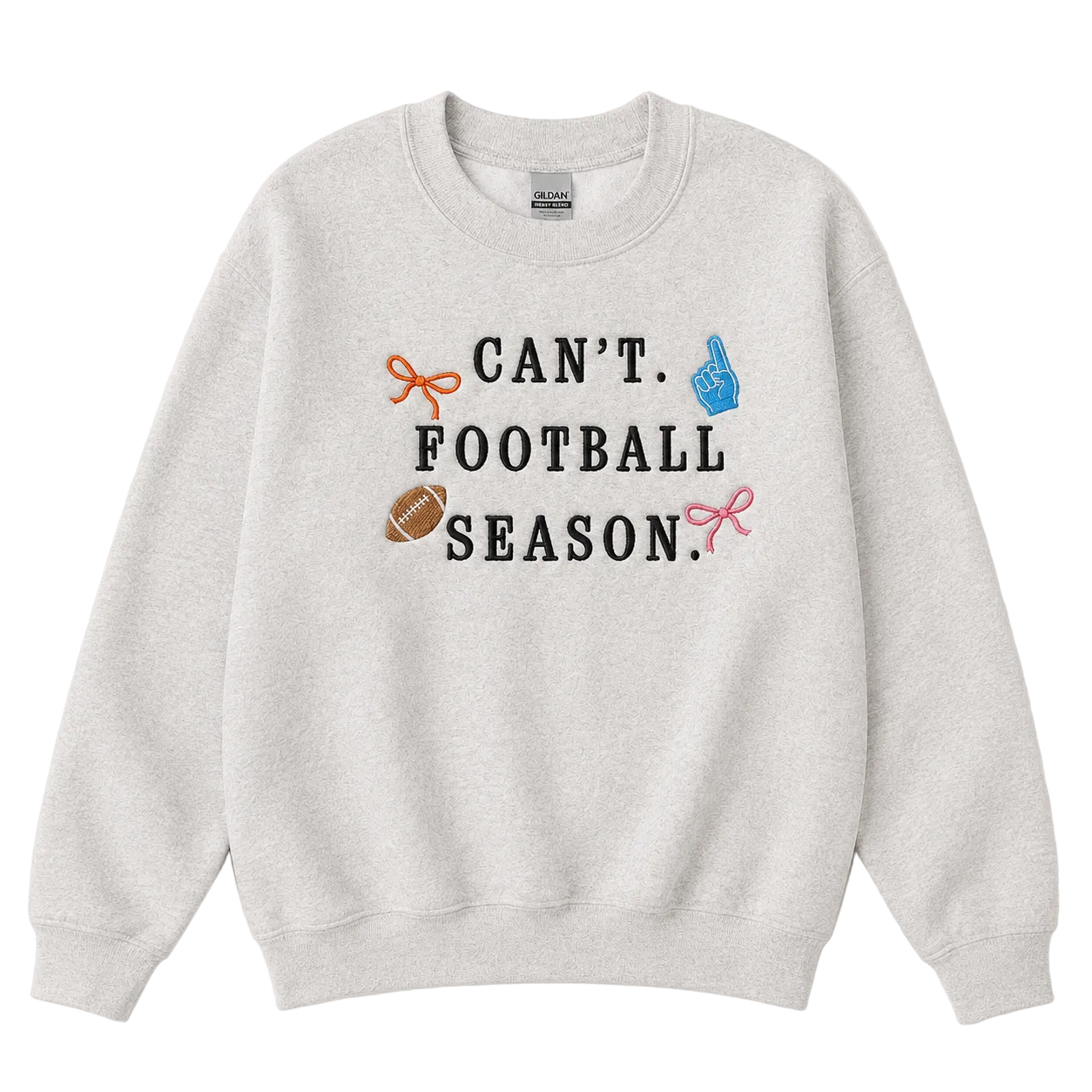 A light heather gray crewneck sweatshirt featuring the text 'CAN'T FOOTBALL SEASON.' in black, decorated with small graphic icons of an orange bow, a blue pointing hand, a brown football, and a pink bow.